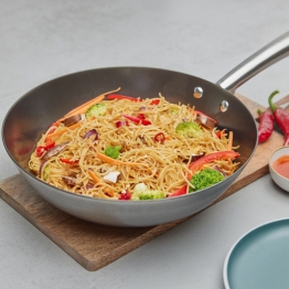 runde, hohe Eisenpfanne mit gebratenem Gemüse