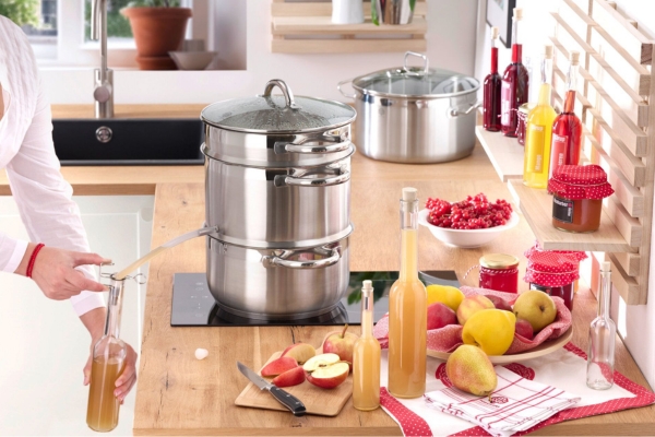 Entsafter in einer Küche, mit frisch gepresstem Saft und Obst