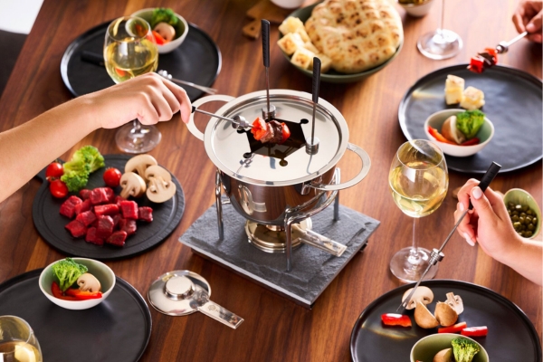 Fondue-Set mit Fleisch, Obst und Gemüse auf einem Tisch