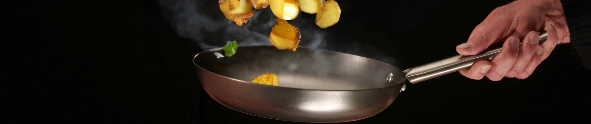 Bratendes Gemüse in einer Eisenpfanne wird geschwenkt in der Luft